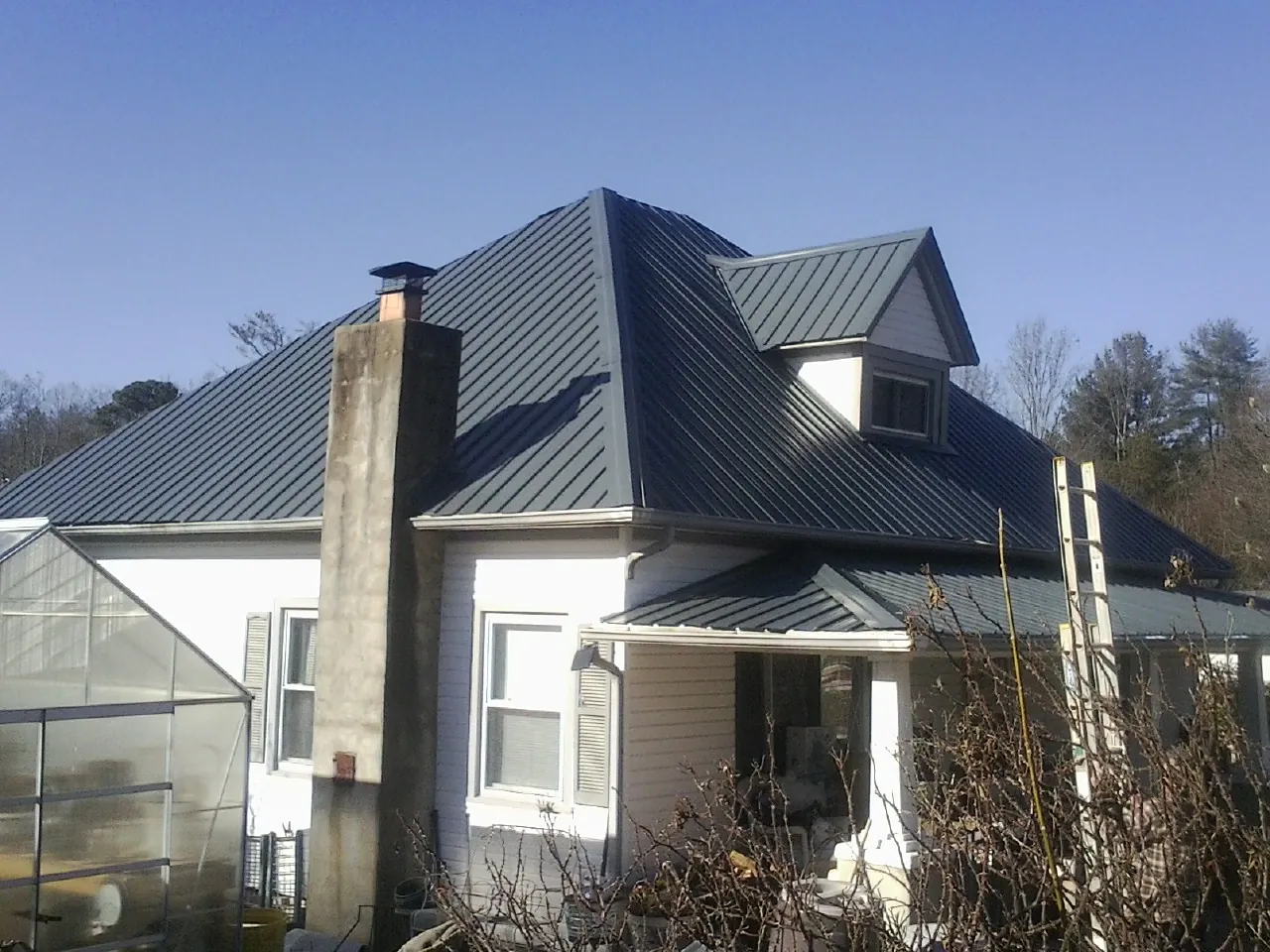 Dark blue standing seam metal roof on a white farmhouse with dormer — Slate & Tile Roof Repair by Roofing Brothers in Bruceton