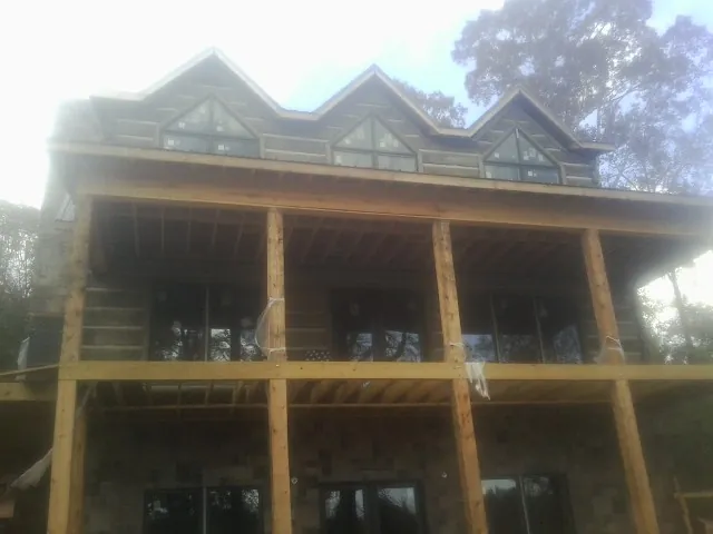 Dormers and porch framing on a large log home under construction — Roof Coating work by our crew in Bruceton