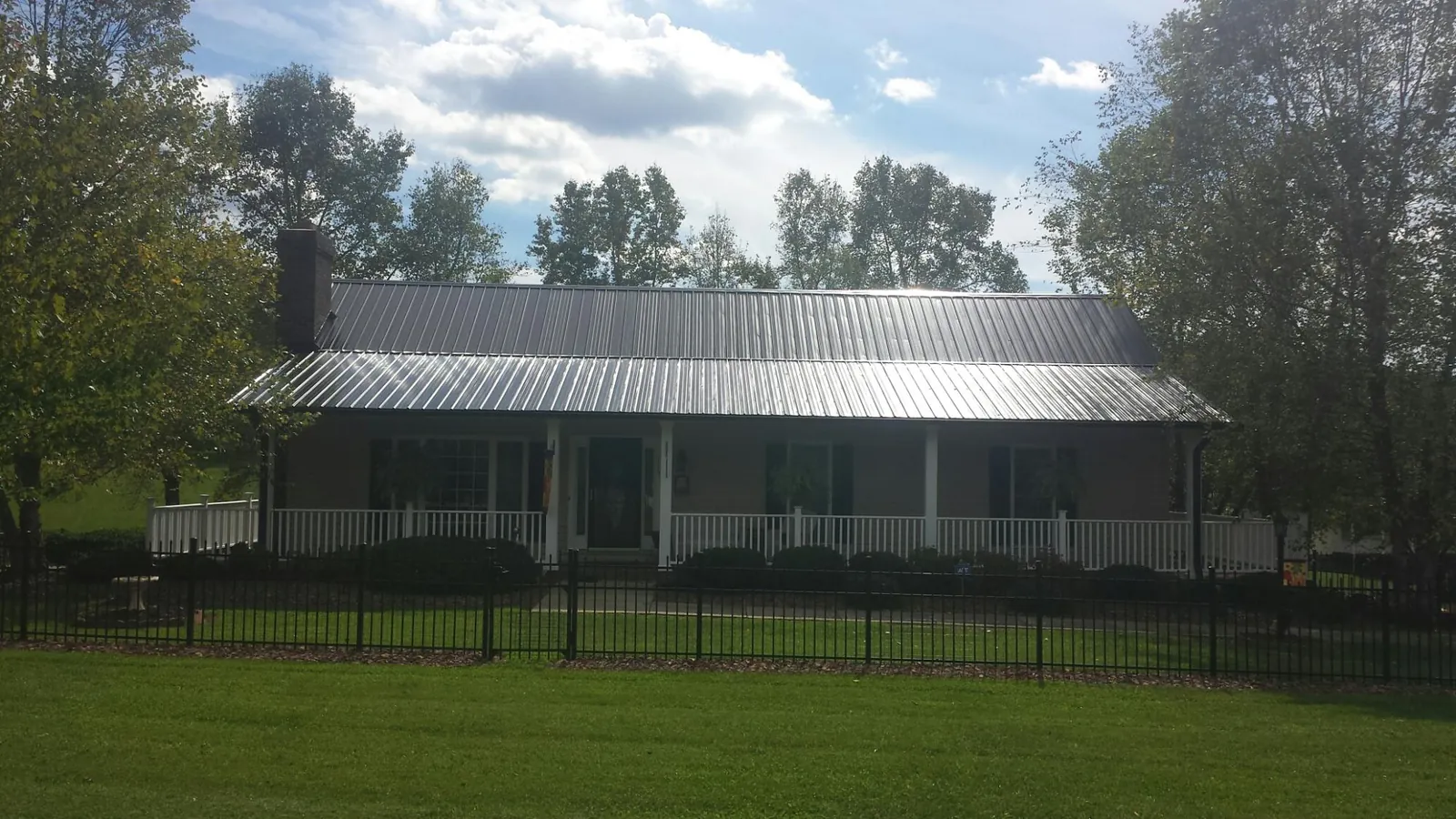 Gray metal roof on a brick ranch with a full width front porch — Gutter Guard Installation work by our crew in Bruceton