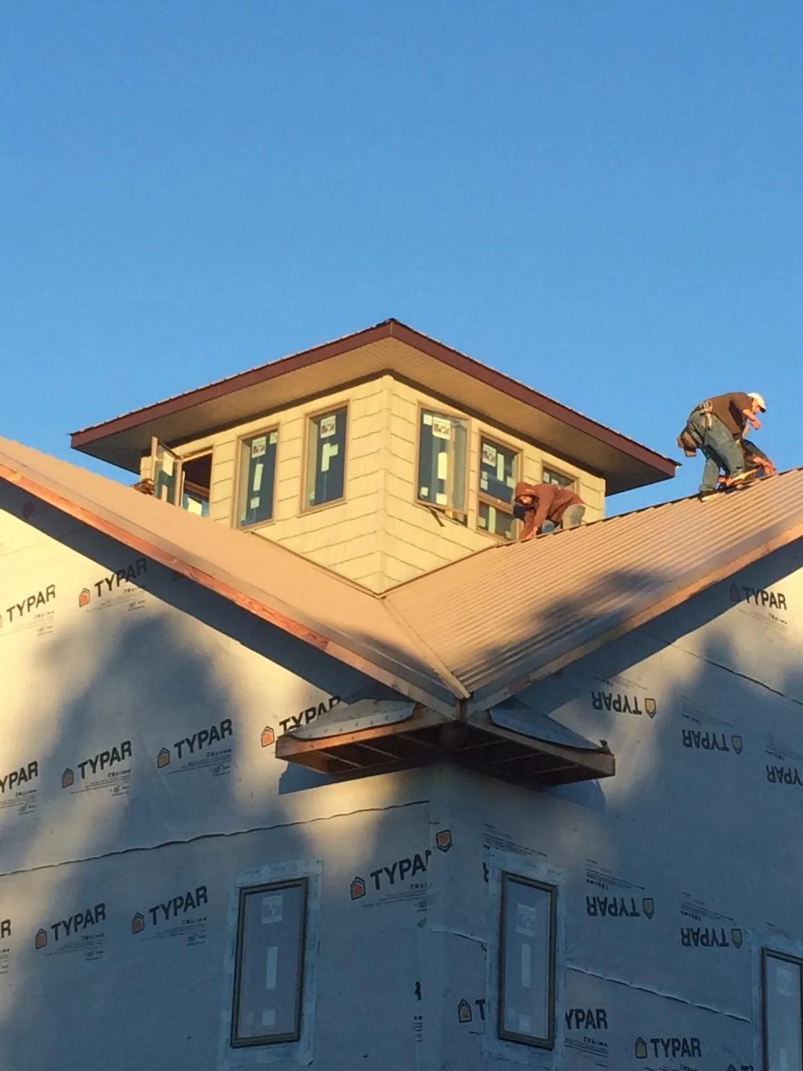 Roofers working around a rooftop cupola on a new metal roof at sunset — Roof Waterproofing in Bruceton by Roofing Brothers